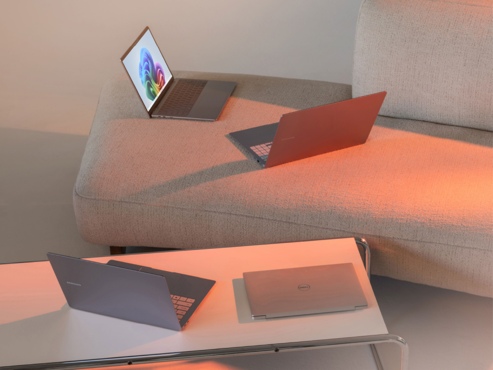 Multiple laptops sitting on a coffee table and sofa